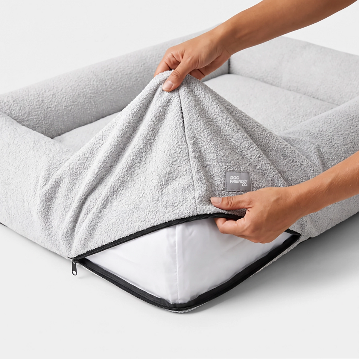 Grey bouclé replacement cover being lifted to show the bed insert and zipper.