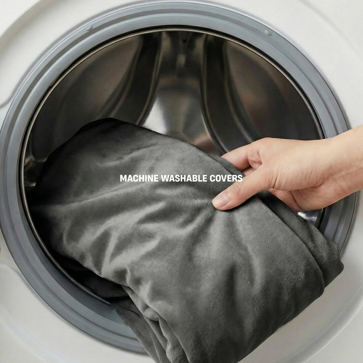 Charcoal dog bed cover being placed into a washing machine with MACHINE WASHABLE COVERS label.