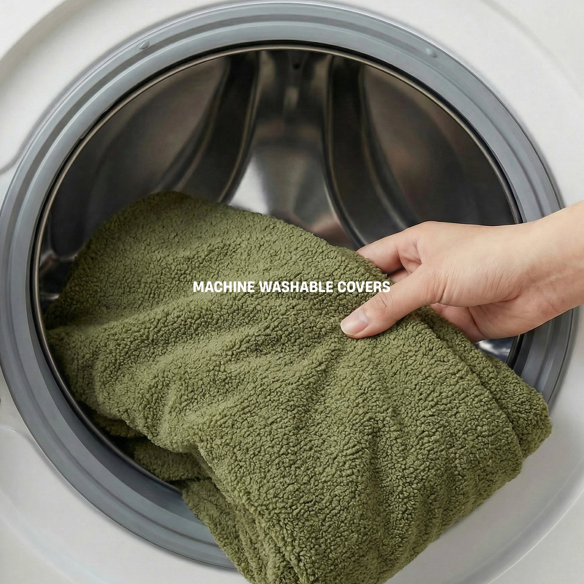 Green Bouclé dog bed cover being placed into a washing machine with MACHINE WASHABLE COVERS label.